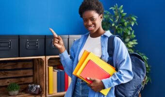 African american woman wearing student backpack and holding books smiling happy pointing with hand and finger to the side